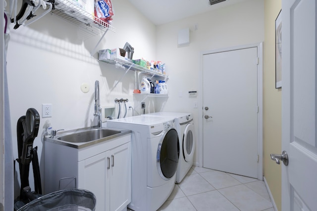 washroom with washer and dryer, light tile patterned floors, cabinets, and sink