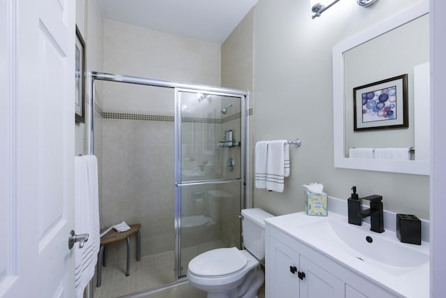 bathroom with tile patterned floors, vanity, toilet, and a shower with shower door