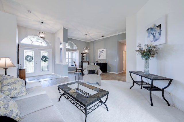 living room with light hardwood / wood-style floors, an inviting chandelier, and french doors