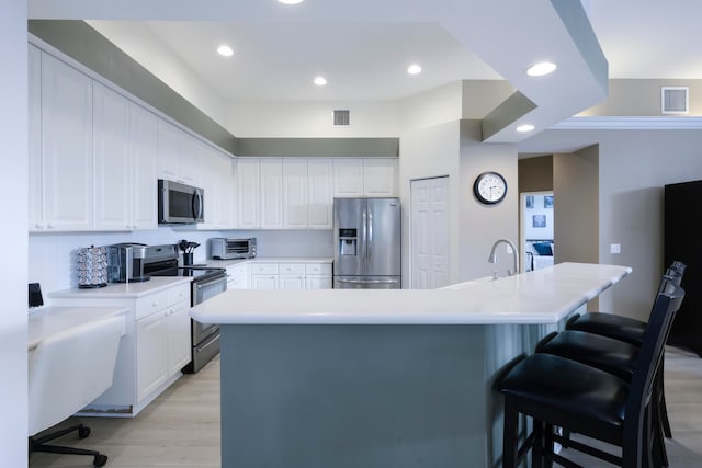 kitchen featuring a large island, a kitchen breakfast bar, white cabinetry, and stainless steel appliances