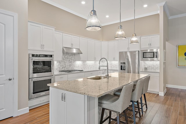 kitchen featuring light stone counters, stainless steel appliances, sink, a center island with sink, and white cabinets