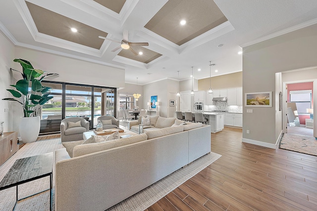 living room featuring beam ceiling, ceiling fan with notable chandelier, coffered ceiling, and ornamental molding