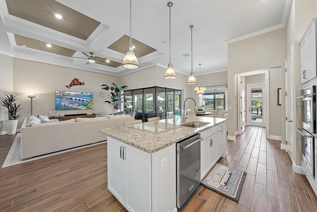 kitchen with a center island with sink, white cabinetry, ceiling fan, and sink