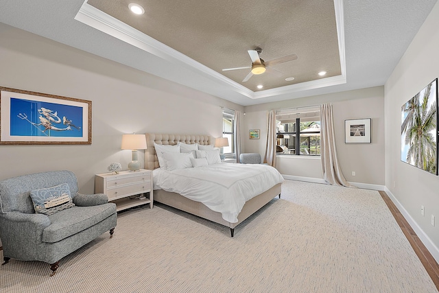 bedroom with a textured ceiling, a raised ceiling, ceiling fan, crown molding, and hardwood / wood-style flooring