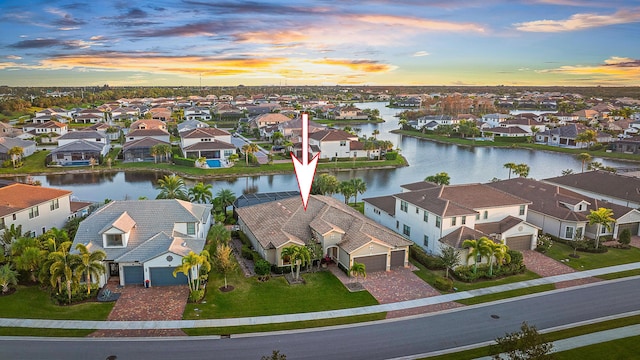 aerial view at dusk featuring a water view