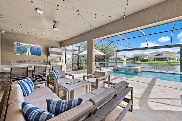 view of patio featuring a water view, an in ground hot tub, and an outdoor living space with a fire pit