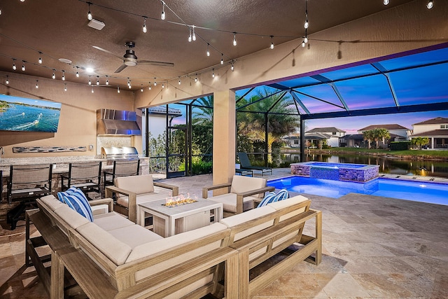 patio terrace at dusk featuring a water view, ceiling fan, a lanai, an in ground hot tub, and an outdoor living space with a fire pit