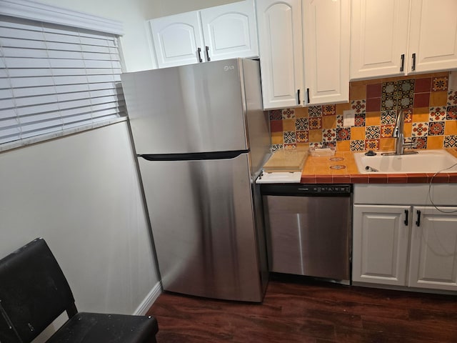 kitchen with tile counters, white cabinets, sink, dark hardwood / wood-style floors, and appliances with stainless steel finishes