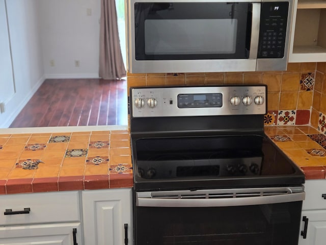 kitchen with tile counters, stainless steel appliances, hardwood / wood-style flooring, and backsplash