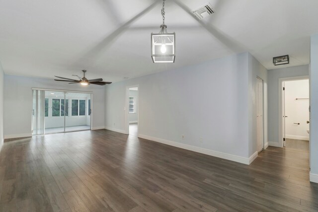 unfurnished living room featuring ceiling fan, a healthy amount of sunlight, and dark wood-type flooring