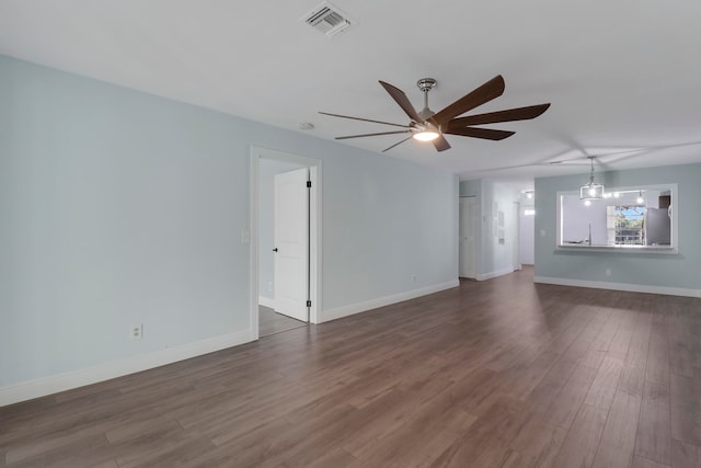 unfurnished living room with ceiling fan with notable chandelier and dark hardwood / wood-style flooring