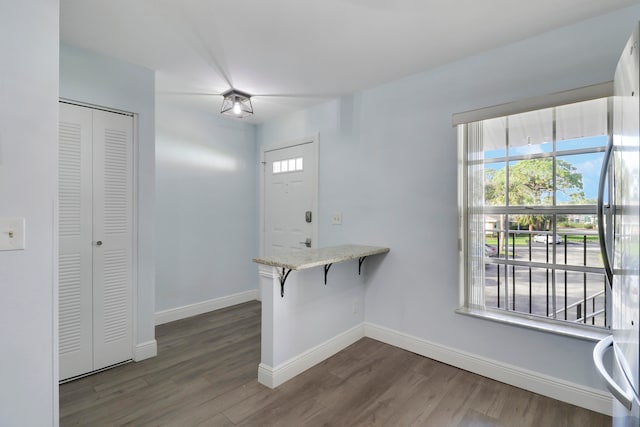 interior space with kitchen peninsula, a kitchen breakfast bar, dark hardwood / wood-style flooring, stainless steel fridge, and white cabinetry