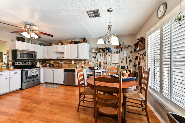 dining area featuring sink, ceiling fan with notable chandelier, a textured ceiling, and light hardwood / wood-style floors