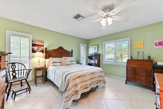 tiled bedroom with ceiling fan and a textured ceiling