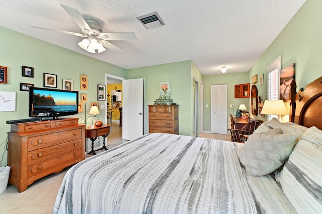 bedroom with light tile patterned flooring, ceiling fan, and a textured ceiling