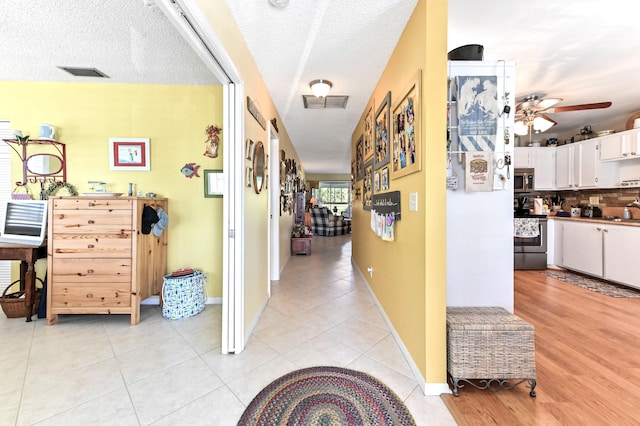 hallway featuring a textured ceiling and light tile patterned flooring