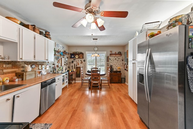 kitchen featuring white cabinetry, decorative light fixtures, light hardwood / wood-style flooring, appliances with stainless steel finishes, and backsplash