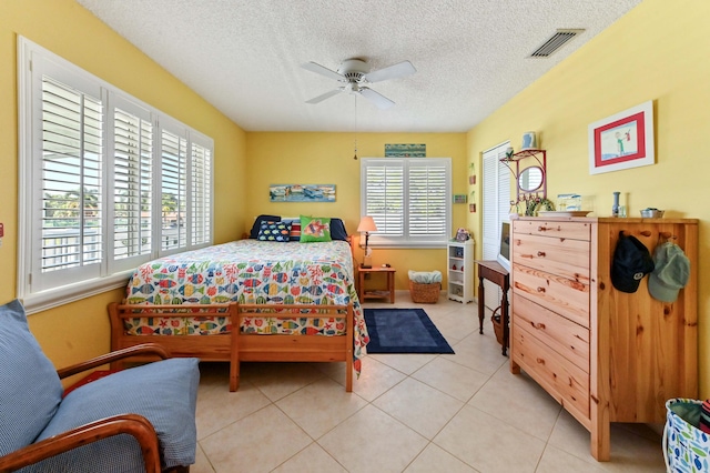 tiled bedroom featuring multiple windows, ceiling fan, and a textured ceiling