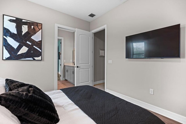 bedroom with ensuite bath and light wood-type flooring