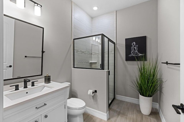 bathroom with hardwood / wood-style floors, a shower with shower door, vanity, and toilet