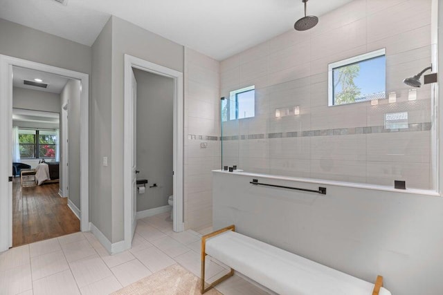 bathroom with toilet, wood-type flooring, and a tile shower