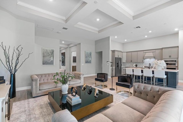 living room with beam ceiling, light hardwood / wood-style flooring, crown molding, and coffered ceiling