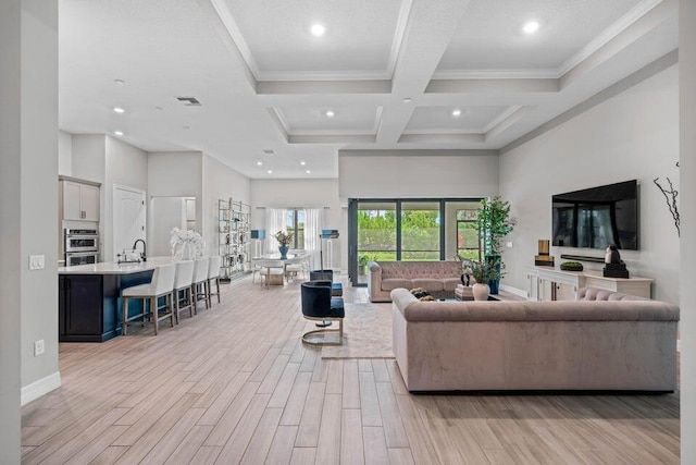 living room with sink, coffered ceiling, beamed ceiling, crown molding, and light wood-type flooring