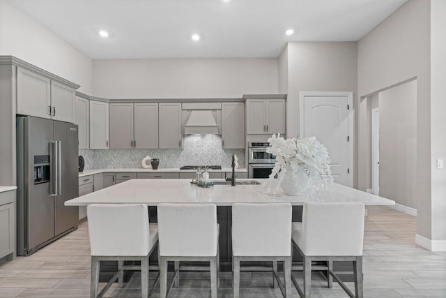 kitchen featuring a large island, gray cabinetry, appliances with stainless steel finishes, and premium range hood