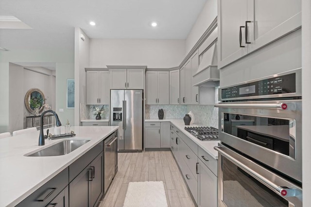 kitchen with light hardwood / wood-style floors, stainless steel appliances, sink, custom exhaust hood, and gray cabinets