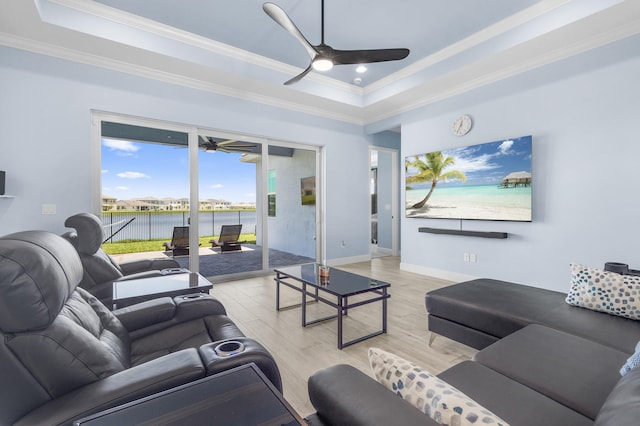 living room featuring light hardwood / wood-style floors, ceiling fan, crown molding, and a tray ceiling