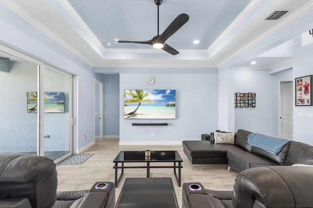 living room featuring light wood-type flooring, a tray ceiling, ceiling fan, and crown molding