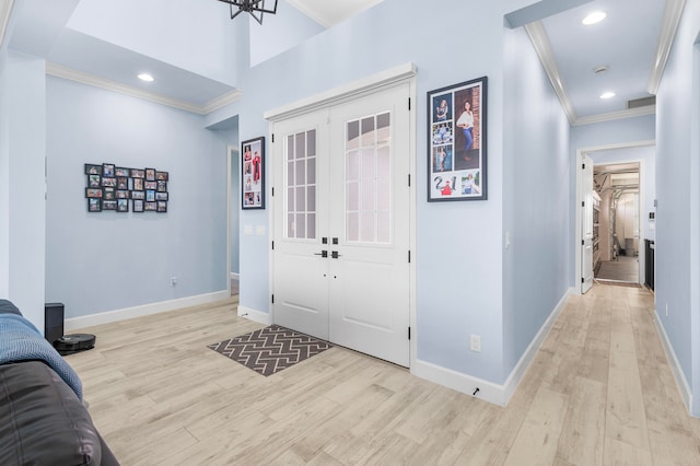 foyer entrance with ornamental molding, french doors, and light hardwood / wood-style flooring