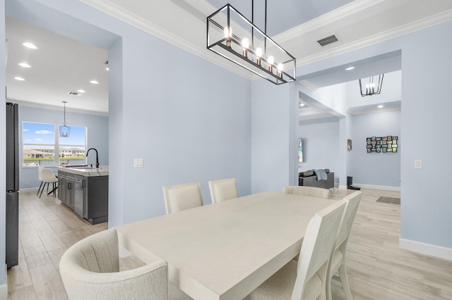 dining space with ornamental molding, light wood-type flooring, and sink