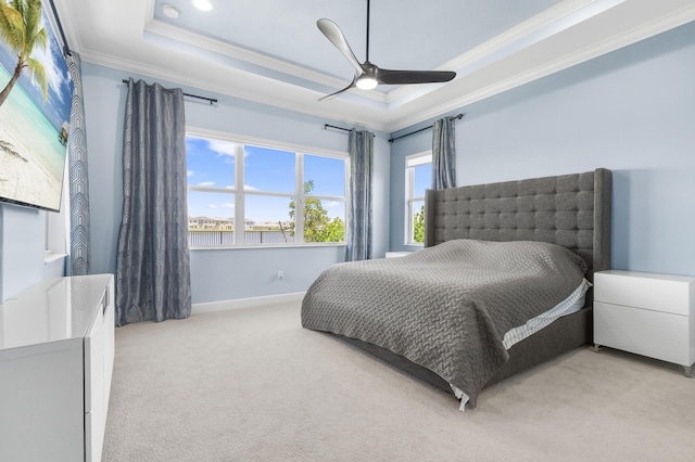 carpeted bedroom with ceiling fan, a raised ceiling, and ornamental molding