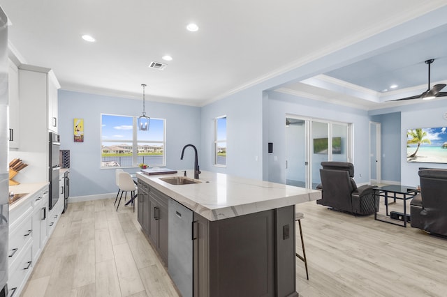 kitchen with white cabinetry, a kitchen island with sink, sink, and decorative light fixtures