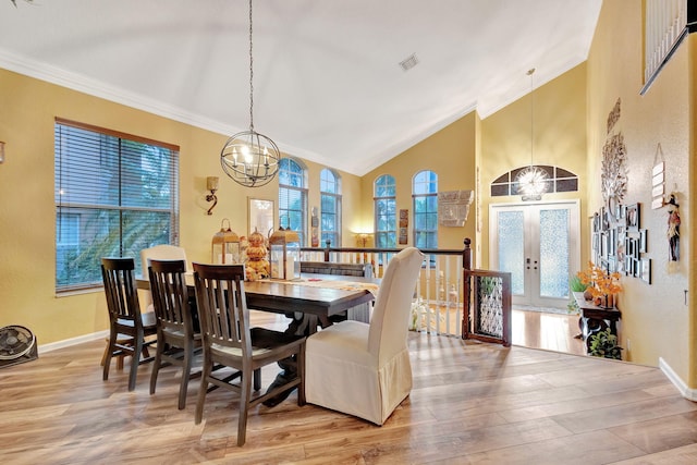 dining room with light wood-type flooring, ornamental molding, and french doors