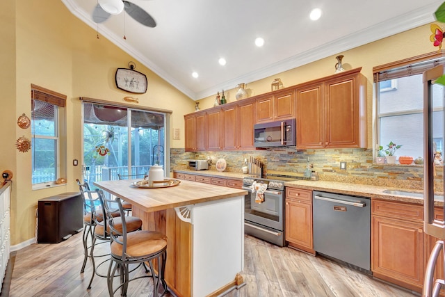 kitchen featuring wood counters, a center island, a healthy amount of sunlight, and stainless steel appliances