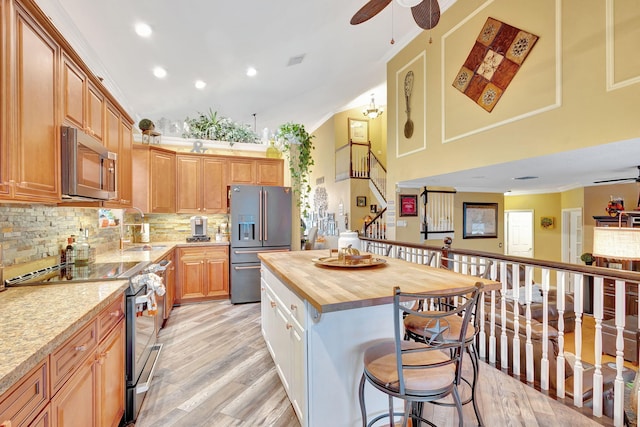 kitchen featuring ceiling fan, light wood-type flooring, butcher block countertops, a kitchen island, and stainless steel appliances