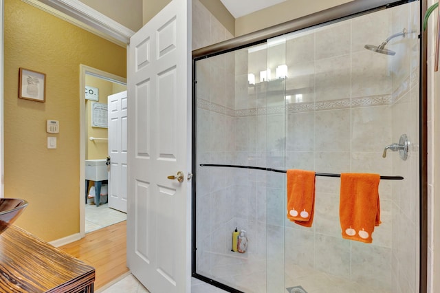 bathroom featuring a shower with shower door, wood-type flooring, and ornamental molding