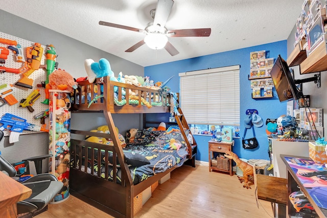 bedroom featuring ceiling fan, light wood-type flooring, and a textured ceiling