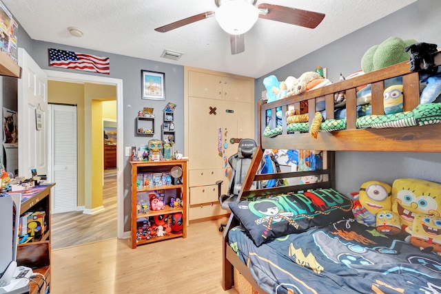 bedroom with ceiling fan, a textured ceiling, and light hardwood / wood-style flooring