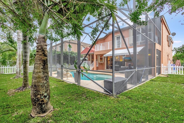 rear view of house featuring glass enclosure, a fenced in pool, a balcony, a yard, and a patio area