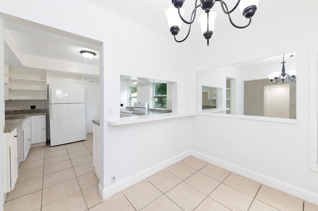 kitchen featuring light tile patterned floors, white appliances, an inviting chandelier, and white cabinetry