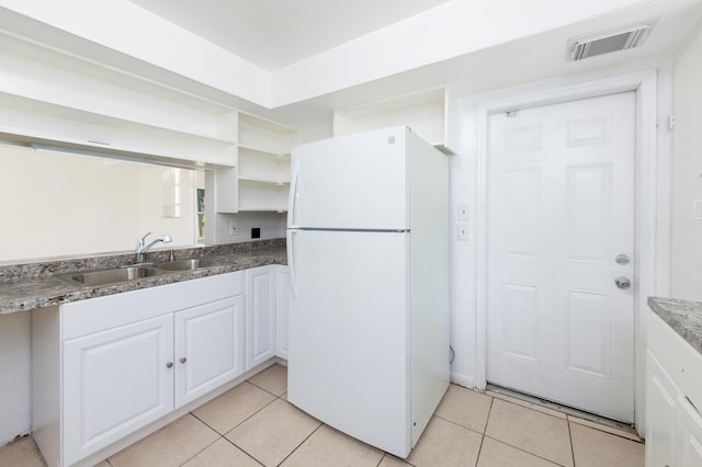 kitchen featuring white fridge, white cabinets, light tile patterned floors, and sink