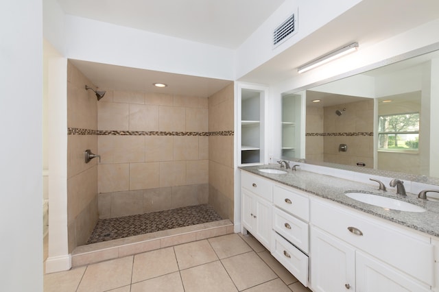 bathroom with tile patterned flooring, vanity, and tiled shower