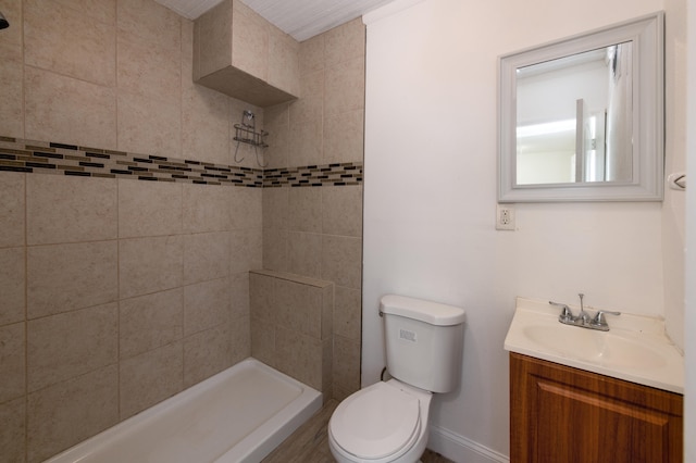 bathroom with tiled shower, vanity, and toilet