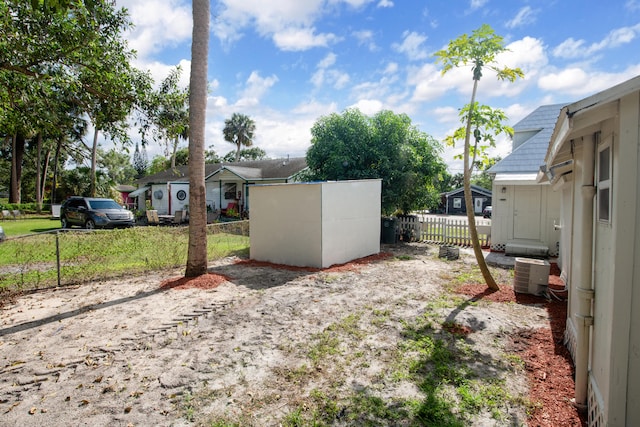 view of yard with central AC and a storage unit