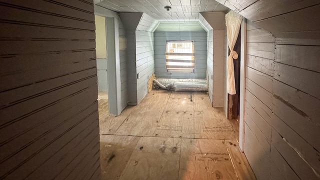 corridor featuring wooden walls and lofted ceiling