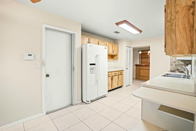 kitchen with light brown cabinets, white fridge with ice dispenser, sink, and light tile patterned floors