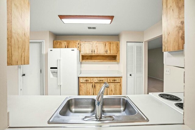 kitchen with light brown cabinetry, white fridge with ice dispenser, white fridge, and sink